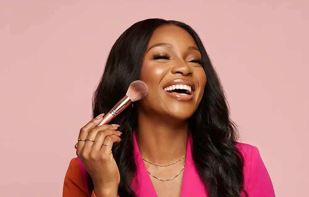 Smiling woman holding a makeup brush before a beauty appointment