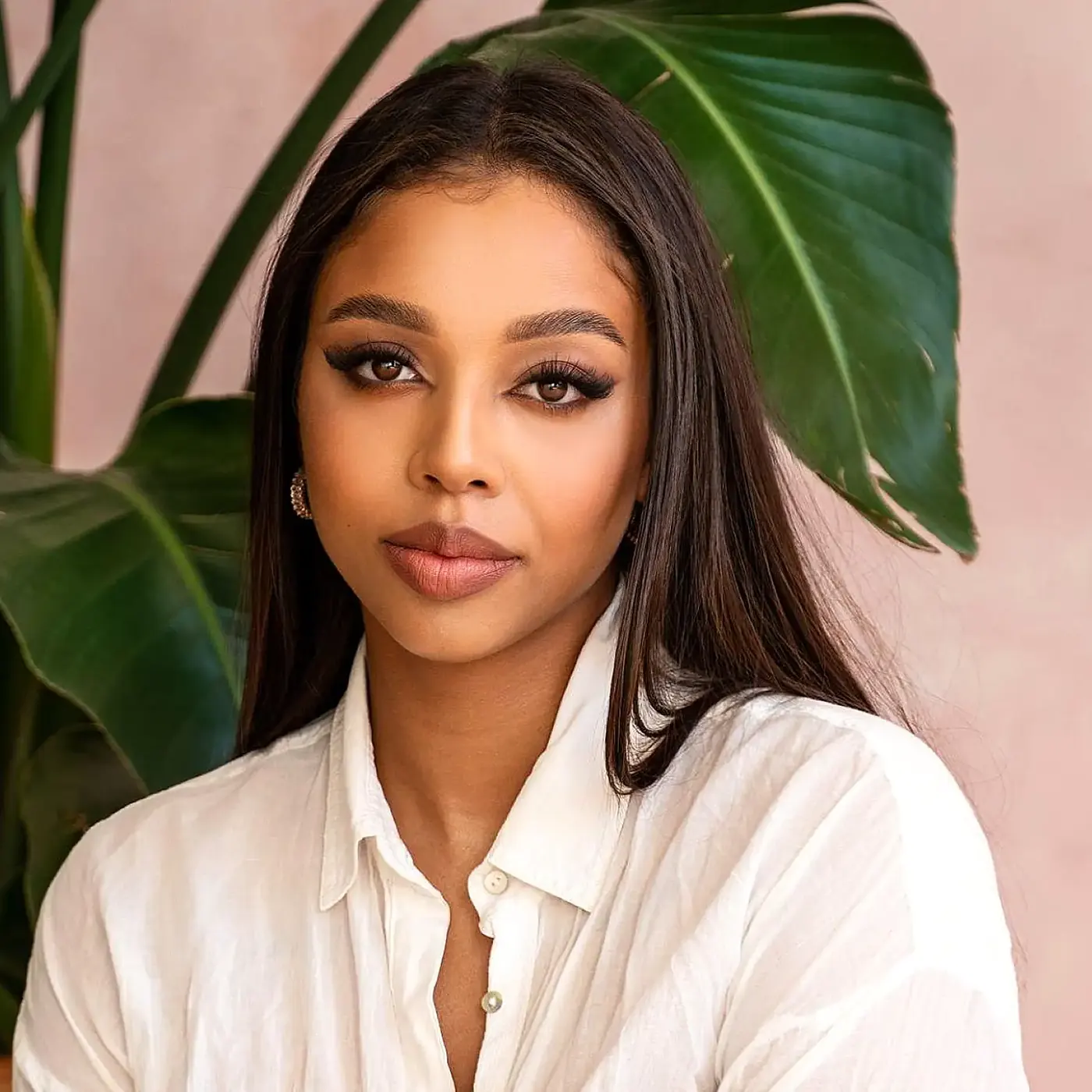 Yewande, a makeup artist, photographed against a plant